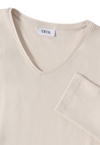 Beige pitkähihaine paita, jossa on V-pääntie, valmistettu sileästä kankaasta, jossa on siisti ompelu ja kaula-aukossa "CECIL"-merkki.