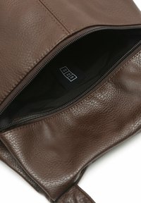 Ruda odinė rankinė su tekstūruotu paviršiumi, su užtrauktuku ir tamsiu vidiniu pamušalu. Matomas vidinis etiketė.