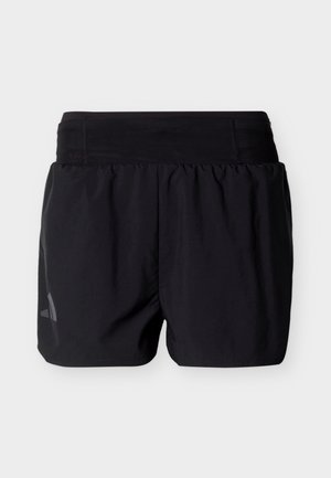 Shorts de sport noirs avec une large taille élastique et un petit logo réfléchissant sur la partie inférieure de la jambe gauche.