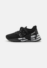 Scarpe sportive nere con una parte superiore in maglia texturizzata, accenti argento a contrasto, una suola ammortizzata e un design geometrico prominente sul lato.