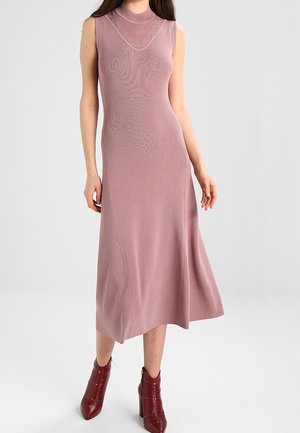 Robe midi mauve sans manches avec col montant et détails en voile transparent, associée à des bottines bordeaux foncé ornées de clous.