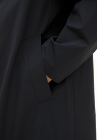 Marineblaue, wasserdichte Jacke mit glatter Textur und einer in die Naht integrierten Seitentasche, die ein einfaches, minimalistisches Design aufweist.