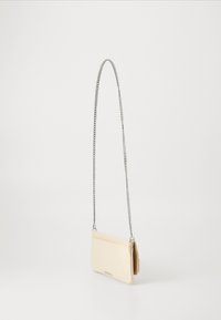 Sac en cuir beige à bandoulière avec une fine chaîne argentée, de forme rectangulaire, texture lisse, doté d'un petit rabat de fermeture.