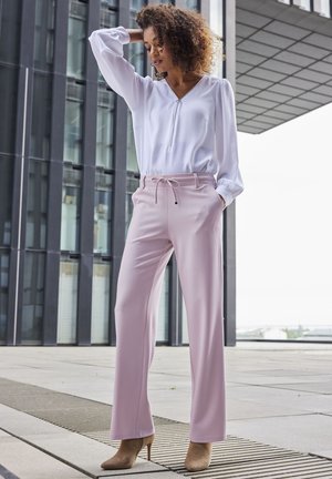Helle rosa Hosen mit geradem Bein und Kordelzugbund, kombiniert mit einer weißen Bluse mit langen Ärmeln und Reißverschlussdetail.