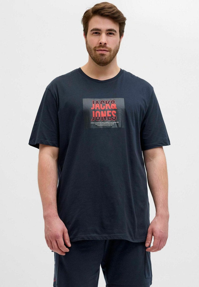 Mørkeblå bomulds T-shirt med et kvadratisk grafik, hvor "JACK & JONES" står med fed rød tekst. Løs pasform med korte ærmer og rund hals.