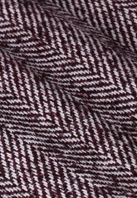 Tissu en chevrons bordeaux et blanc, présentant un tissage texturé avec un motif diagonal. Doux avec des fibres visibles partout.