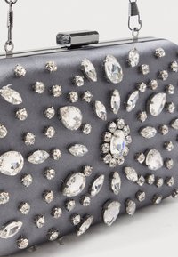 Szara satynowa kopertówka ozdobiona kryształkami w różnych rozmiarach i kształtach, z metalowym, srebrnym zapięciem i łańcuszkowym uchwytem.