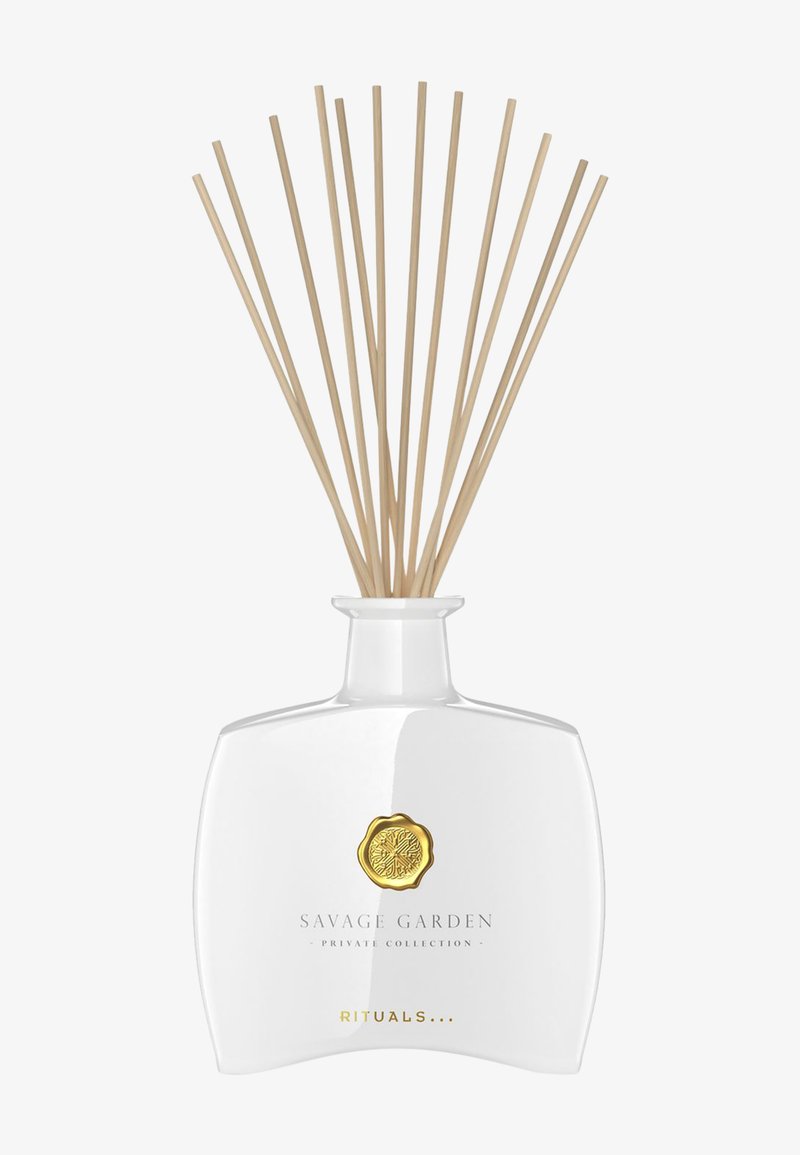 Flacon diffuseur en verre transparent avec emblème doré et tiges en roseau naturel, étiqueté "Savage Garden Private Collection" de Rituals.