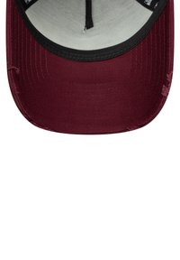 Interior de una gorra marrón con visera negra, costuras visibles y un forro suave de color gris claro. Muestra un ligero desgaste a lo largo del borde.