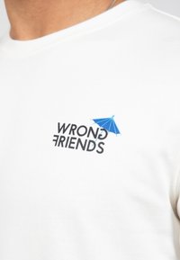 Bílé bavlněné tričko s nápisem "WRONG FRIENDS" v černé barvě a modrou grafikou deštníku nad nápisem. Minimalistický design.