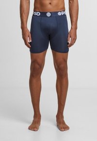 Boxer-briefs pour hommes en bleu marine en tissu extensible, avec une taille noire arborant le logo "PSD". Texture lisse et design ajusté.