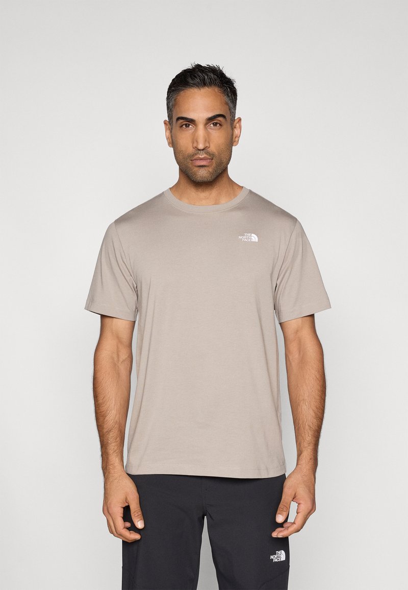 Μπεζ κοντομάνικη μπλούζα με στρογγυλή λαιμόκοψη από απαλό βαμβάκι· διαθέτει μικρό λευκό λογότυπο στο πάνω αριστερό μέρος του στήθους.