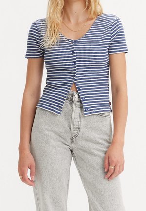 Woman wearing a blue and white striped short-sleeve buttoned crop top and high-waisted light gray jeans, shown from neck to hips.