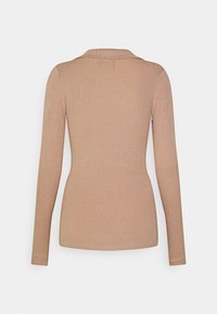 Ribbed, pitkähihainen paita vaaleanruskeana, jossa on kaulus. Kangas näyttää pehmeältä, ja siinä on kapea siluetti ja teksturoitu kuvio.