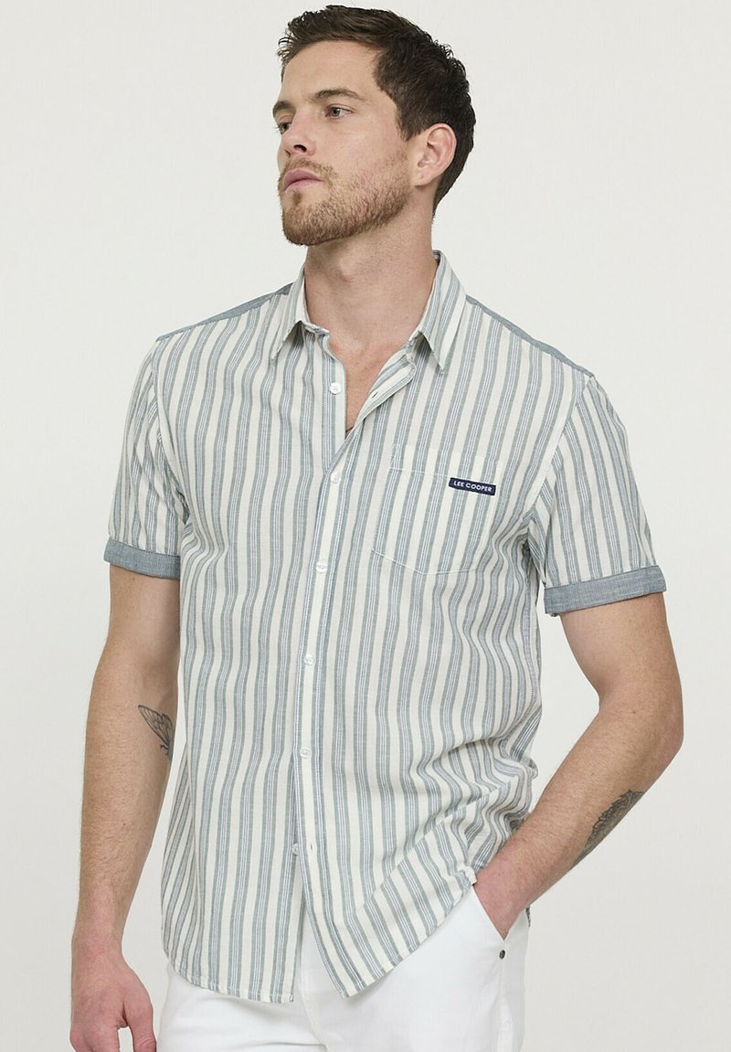 Chemise à manches courtes en beige clair et rayures grises. Comprend une poche poitrine, des manches retroussées, et une étiquette indiquant "Lee Cooper".