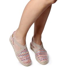 Värikäs kudottu espadrille, jossa on beige joustava remmi ja punottu jutsopohja. Yläosassa on monivärinen kuvio.