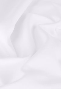 Vitt tyg med en slät textur, som visar mjuka fallande veck och en subtil lyster. Lättviktigt och enhetligt i färgen.
