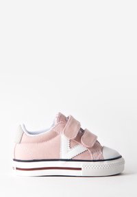 Zapatilla de lona rosa con correas de Velcro blancas, puntera redonda y suela de goma que presenta rayas rojas y azul oscuro a lo largo de la base.