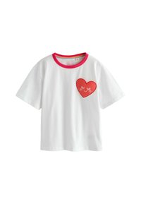 Bela bombažna majica s kratkimi rokavi, rožnato rebrastim ovratnikom in rdečo srčno zaplatjo z nasmejanim obrazom na levi strani prsnega koša.