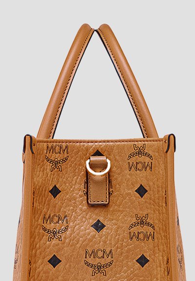 Sac à main en cuir marron MCM avec double poignée, logo noir et motifs en diamant, ainsi qu'une sangle avant avec détail en anneau doré.