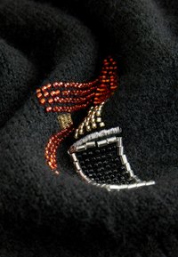 Țesătură neagră cu broderie complexă din mărgele în nuanțe metalice de argint, aur și roșu, reprezentând un design stilizat de păr.