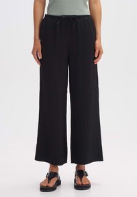 Black wide-leg pants with a textured, ribbed design, featuring an elastic waistband and adjustable drawstring. Flat front pockets are visible.