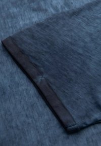 T-shirt blu navy con un tessuto leggermente strutturato, caratterizzato da un orlo dritto e un bordo scuro a contrasto lungo la manica.