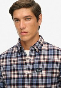 Kariertes Hemd mit Button-Up in Marineblau, Rot und Weiß. Mit klassischem Kragen, Brusttaschen und einem Logopatch auf der linken Brust. Strukturierten Stoff.