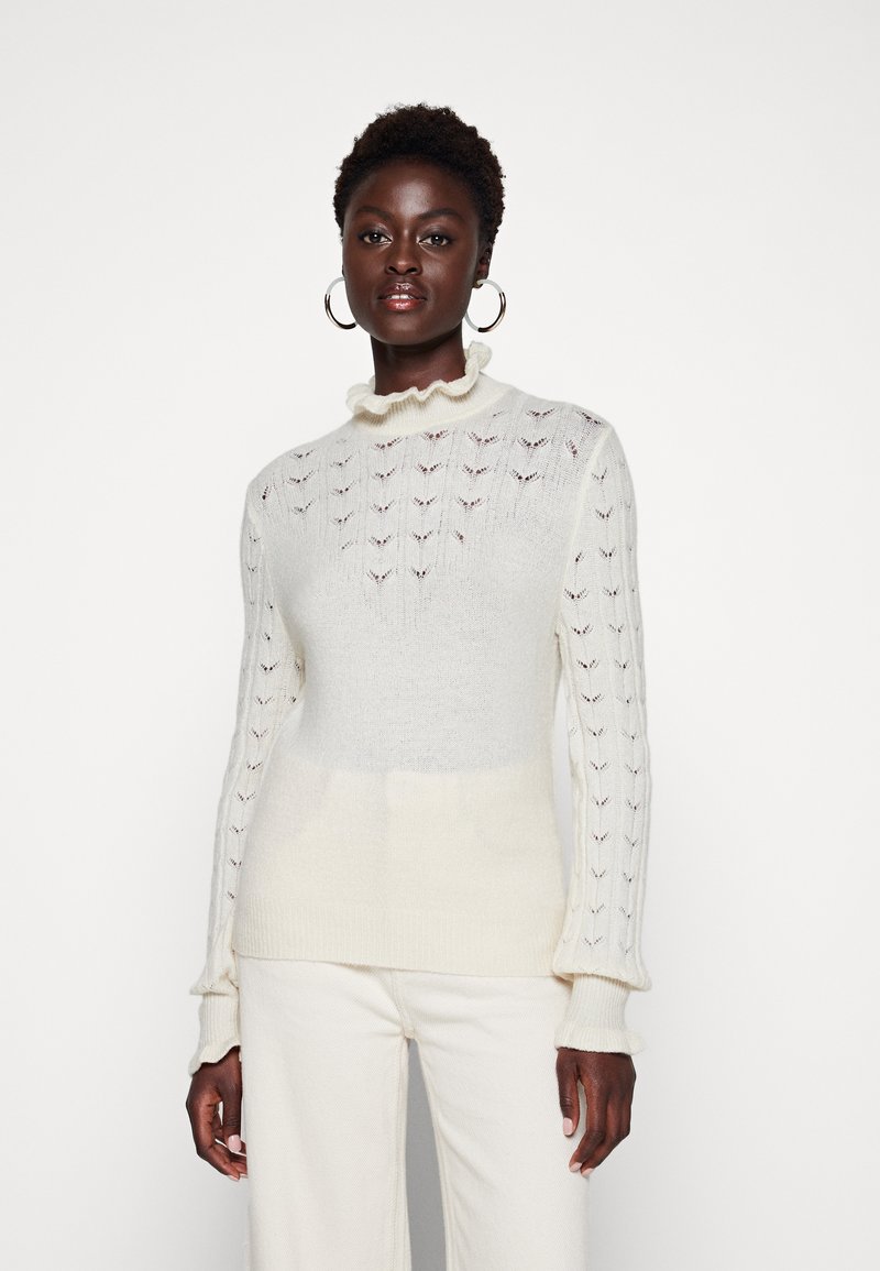 Pullover di colore crema chiaro in tessuto a maglia texture, con scollatura arricciata e maniche lunghe e aderenti. Materiale morbido e leggero.