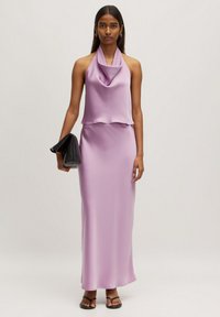 Lila satijnen halterjurk met een gedrapeerde kraag, slim fit en een lange rok tot de grond. Gecombineerd met een zwarte clutch en sandalen.