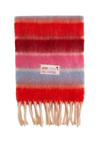 Uldtæppe med store striber i rød, pink og blå nuancer. Omfatter frynsekanter og et mærke med påskriften "GODE TING ER PÅ VEJ."