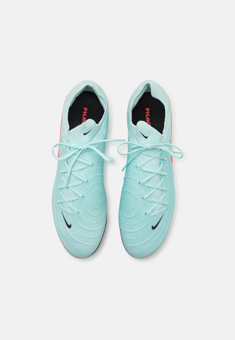 Zapatillas deportivas de color azul claro con parte superior texturizada, cordones planos y el logo de Nike en negro. Presentan un brillante acento rojo en el talón y un forro interior negro.