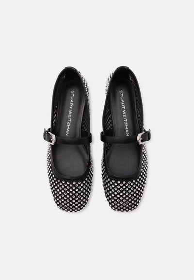 Paire de chaussures Mary Jane noires avec clous argentés et brides à boucle, étiquetées Stuart Weitzman, vues de dessus sur fond blanc.