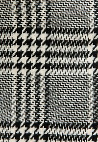 Tejido tejido con un patrón de pata de gallo en blanco y negro, con una superficie texturada que enfatiza formas geométricas y colores contrastantes.