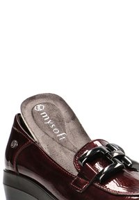 Zapato de charol burdeos con tacón en cuña, que presenta una hebilla decorativa negra y una plantilla acolchada gris con la marca "mysoft".