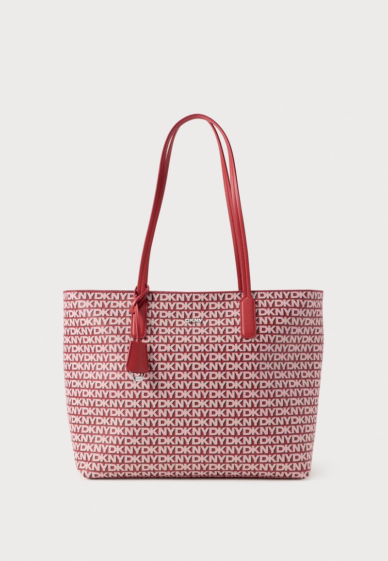 Punane ja valge lõuendist kandekott, millel on kogu ulatuses logomuster, topeltkäepidemed ja väike logokujuline ripats. Sile tekstuur ja struktureeritud kuju.