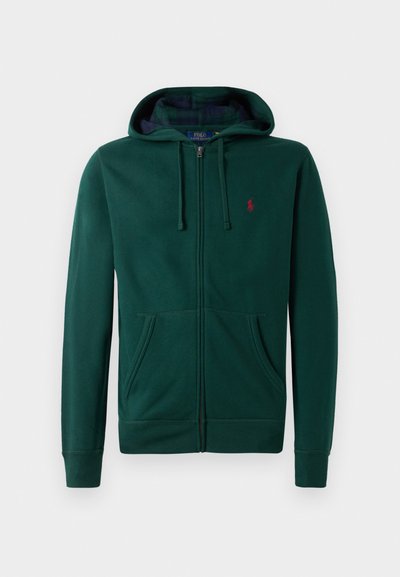 Sweatshirt verde com fecho, feito de material suave, com um fecho central, dois bolsos frontais, punhos canelados e um logótipo vermelho no peito.