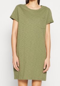 Olive green dress T-shirt wykonany z teksturowanej tkaniny, z krótkimi rękawami i kieszenią na piersi. Prosty krój z luźnym dopasowaniem.