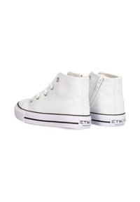 Zapatillas altas blancas de lona con ojales de metal plateado. Presentan una cremallera lateral y una suela de goma negra a rayas con logotipo.