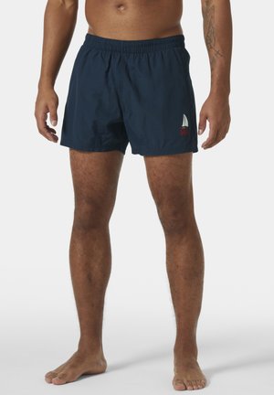 Navy blue swim shorts with an elastic waistband, lightweight material, and a small embroidered sailboat logo. Short length and simple design.
