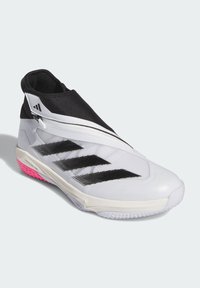 Weiße Sportschuhe mit einer schwarzen sockenähnlichen Oberseite, drei schwarzen Streifen, pinkem Akzent an der Sohle, strukturiertem Oberflächenmaterial und einem einzigartigen Reißverschlussverschluss.