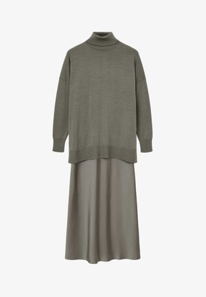 Olivengrøn højhalset sweater lagdelt over matchende langt, flydende skørt på hvid baggrund.