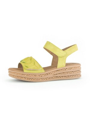 Yellow suede sandals featuring ruffled accents, a cork wedge sole with cutouts, and an adjustable ankle strap for secure fit.