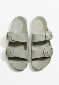 Szürke gumi szandálok, két állítható csatokkal, nyitott orrú dizájnnal és kontúros talpbetéttel a kényelem érdekében. Simaszemcsés felület minimalista részletekkel.