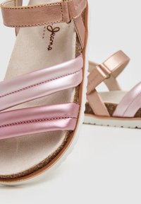 Roze strappy sandalen met glanzend roze faux leer en een kurken voetbed. De zool is wit met lichte ribbels voor extra grip.