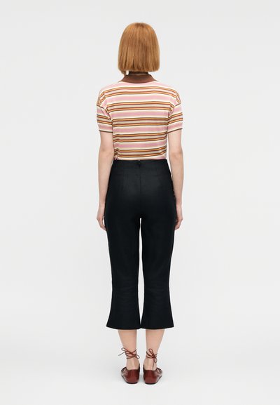 Κοντομάνικο πουκάμισο με ρίγες σε ροζ και πορτοκαλί αποχρώσεις, συνδυασμένο με μαύρο, κοντό παντελόνι με φαρδιά μπάση και καφέ παπούτσια με κορδόνια.