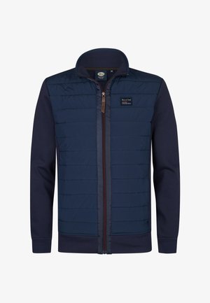 Marineblaue Jacke mit glattem, gesteppetem Oberteil und festem unteren Teil. Verfügt über einen hohen Kragen, einen vorne liegenden Reißverschluss und ein Patch-Logo auf der Brust.