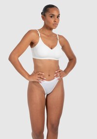 Soutien-gorge sans fil blanc et string assorti en tissu lisse, avec des bretelles réglables et un design simple et minimal.