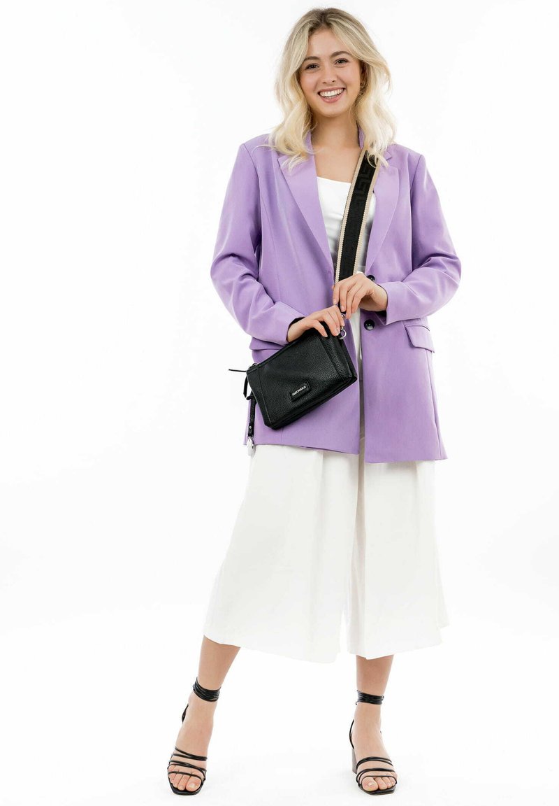 Lavendel blazer med struktureret pasform, parret med hvide vide bukser. Sort crossbody taske har tekstureret overflade og lynlåsdetalje. Sorte hæle.