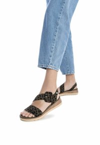Sandalias de estampado de leopardo con parte superior de tela suave, hebilla ajustable y suela beige acolchada, combinadas con pantalones cropped de mezclilla claros.